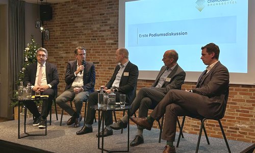 Fünf Männer bei einer Podiumsdiskussion auf einer Bühne