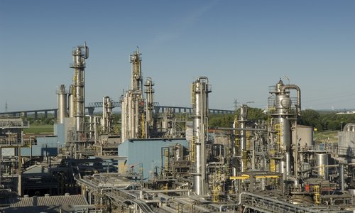 Chemieanlage mit hohen Destillationskolonnen unter blauem Himmel