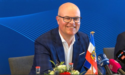 Mann mit Brille bei einer Pressekonferenz mit Mikrofonen