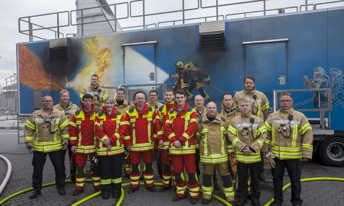 Gruppenfoto von Feuerwehrleuten vor einem Löschübungscontainer