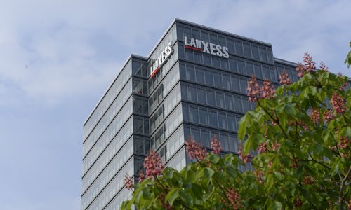Hochhaus mit Lanxess-Schriftzug, im Vordergrund blühende Kastanie