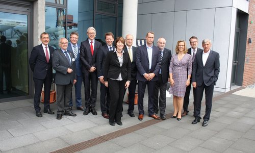 Gruppenfoto von zwölf Personen vor einem modernen Gebäudeeingang