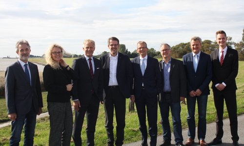 Gruppenfoto von acht Personen in Geschäftskleidung am Elbdeich